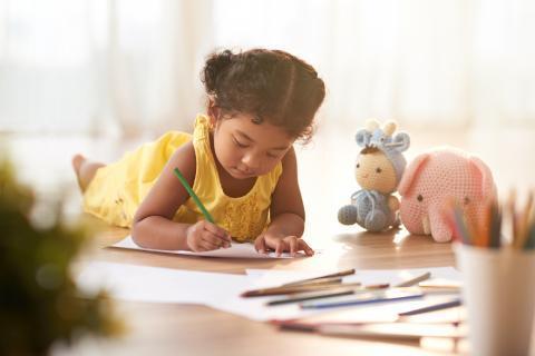 Young girl laying on floor while coloring