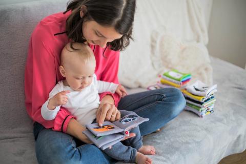 Woman reading a book to baby in lap.