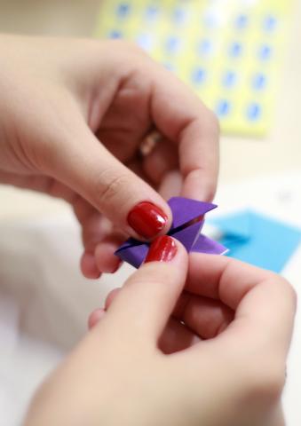 Hands folding paper into origami.