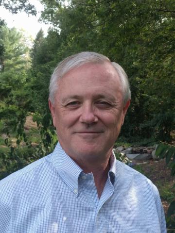 man in blue shirt standing in front of trees