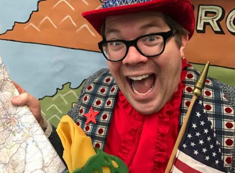 Person dressed in patriotic hat and vest with a map, torch and American flag.