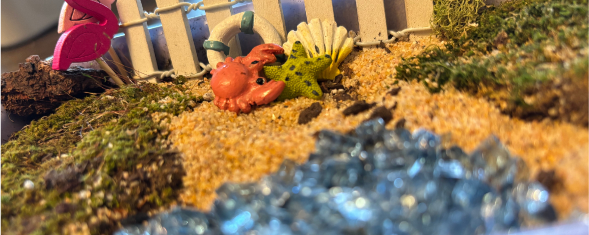 Tiny garden with sand and green moss with tiny flamingo, crab and starfish